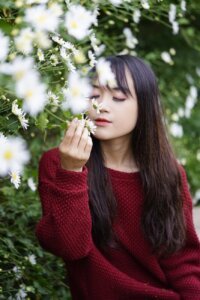 Pre-teen smelling chamomile flower in garden after getting empowered by #CurioCamps Mindfulness Workshop by CurioBuddy. Join our free Mindfulness Workshop for kids aged 9-12. Help them improve focus, manage emotions, and prepare for teenage for success.